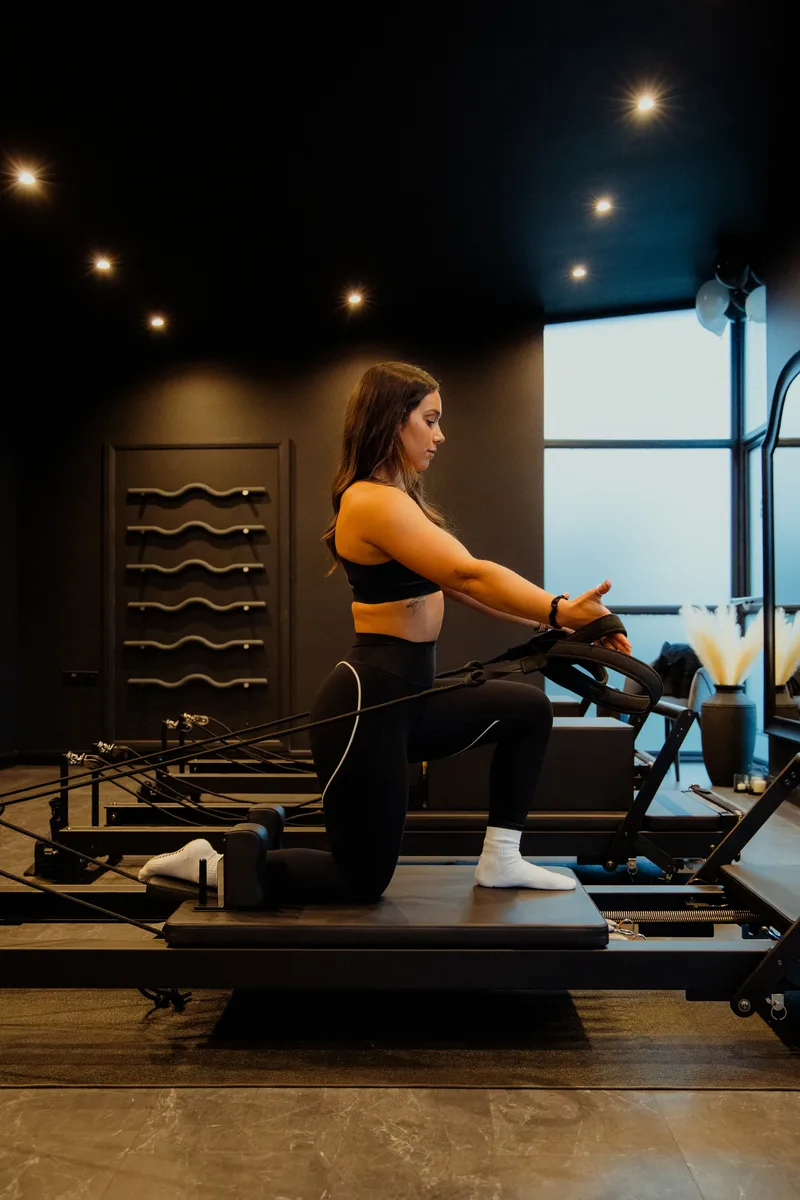 Nadia demonstrating a reformer Pilates exercise with straps at Vit&aacute;lis Studios