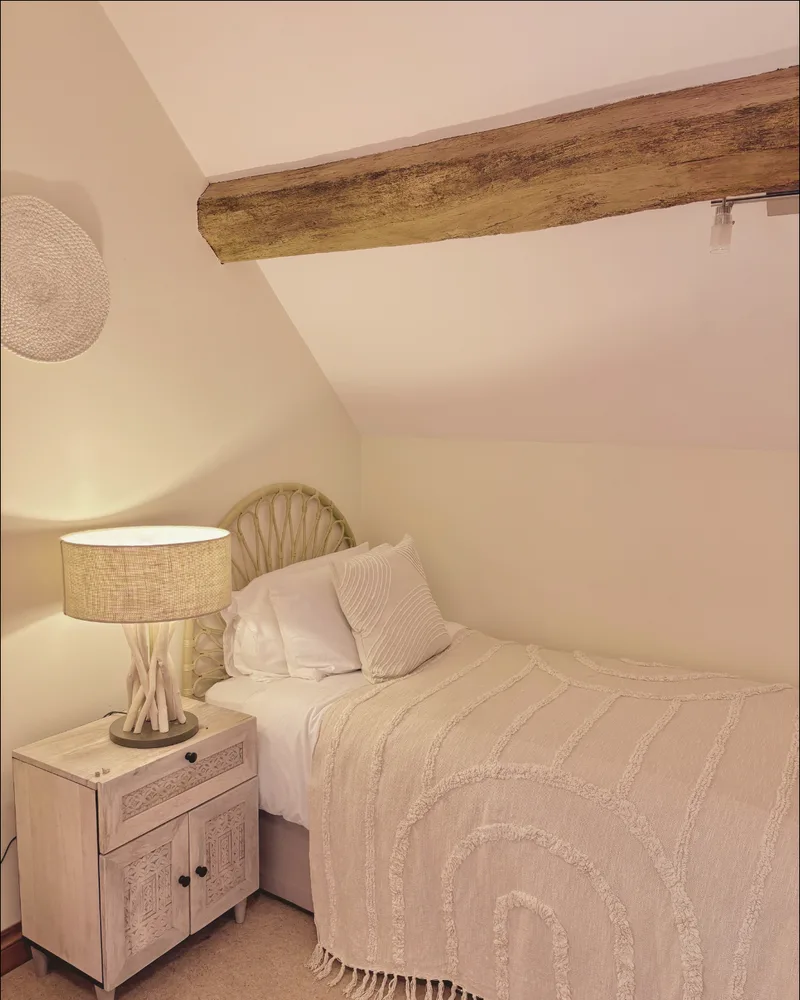 Single bed under a sloped ceiling with an exposed wooden beam