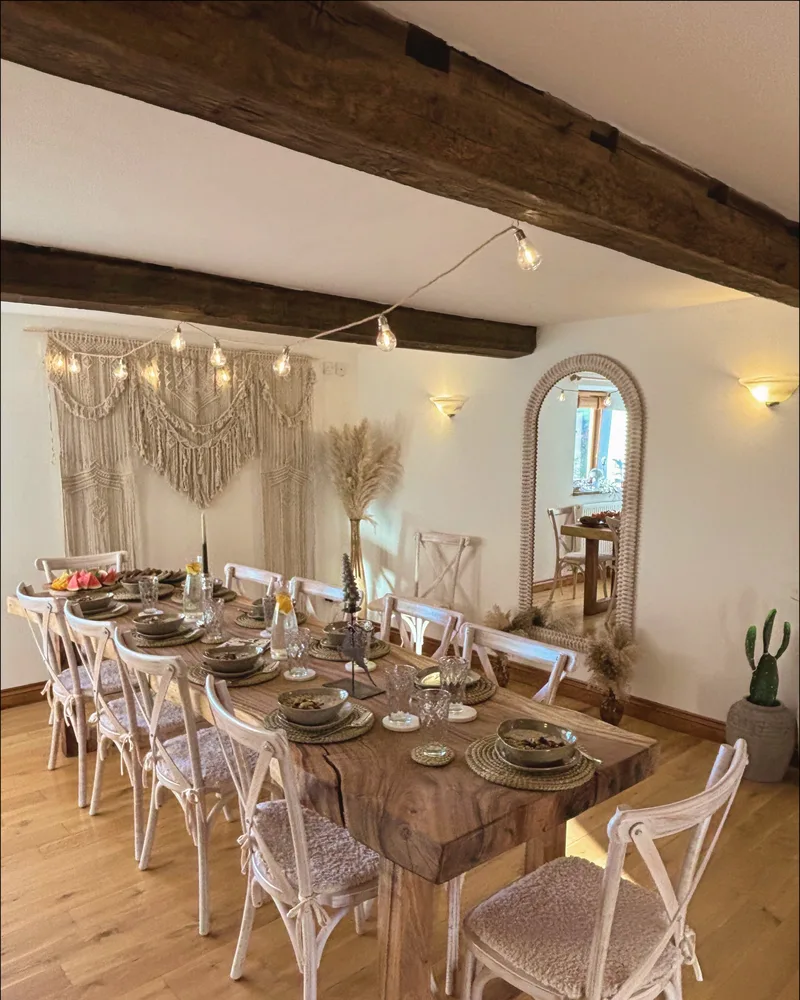 Long wooden dining table set for dinner, with macram&eacute; and warm lighting