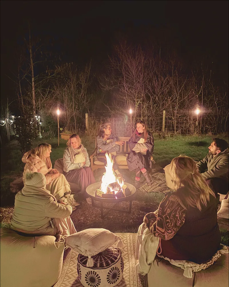 Outdoor fire pit with guests gathered around at dusk