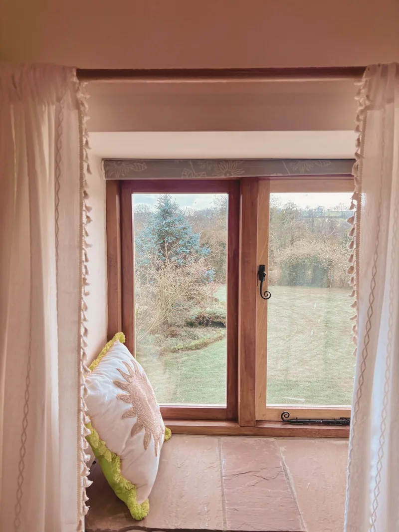 Cosy window nook with layered curtains and Peak District view
