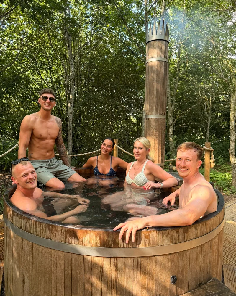 Retreat guests relaxing together in a wood-fired hot tub in the trees