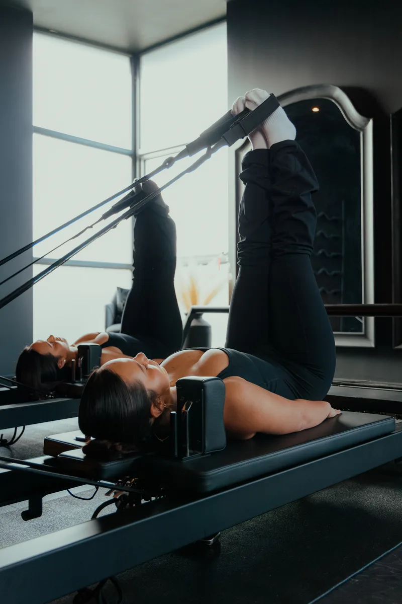 Clients on reformers using leg straps at Vitális Studios